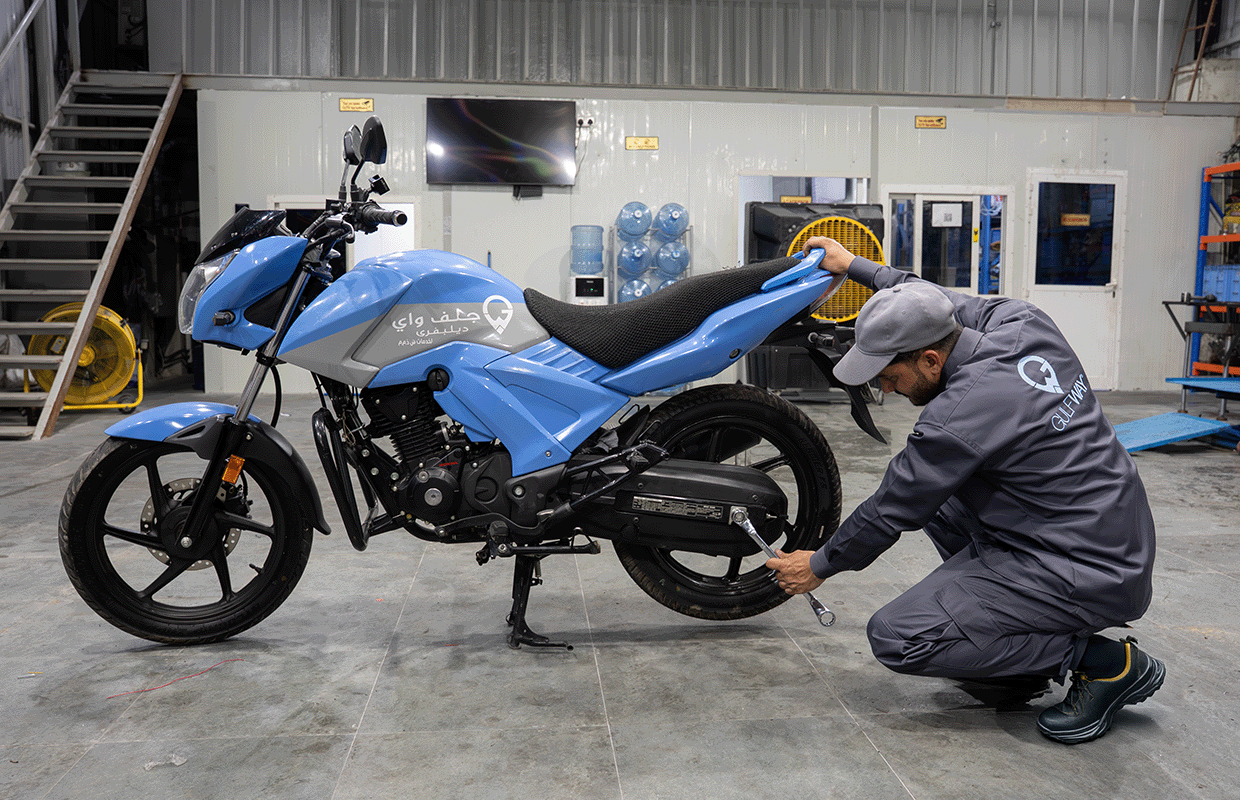 Gulf Way Auto Services mechanic adjusting a motorcycle wheel, demonstrating expertise in bike repair and maintenance.