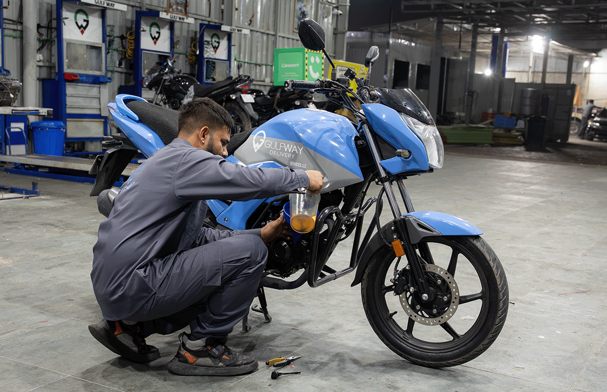 Gulf Way Auto Services technician performing a precise oil change on a Gulf Way Delivery motorcycle, ensuring engine health.
