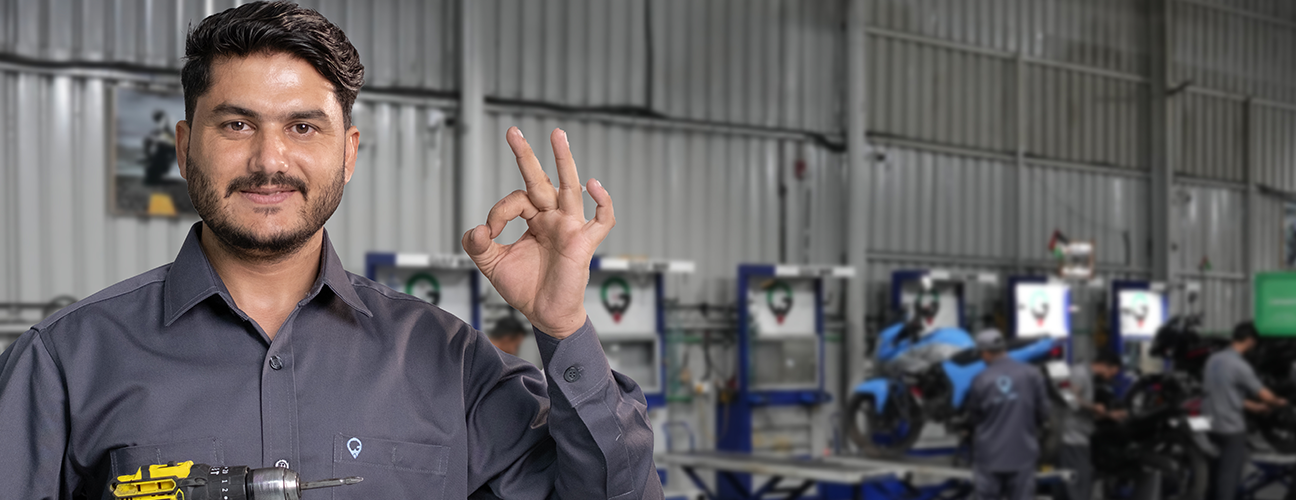 Smiling Gulf Way Auto Services expert mechanic showing an "okay" sign in a modern workshop, representing quality auto and bike repair.