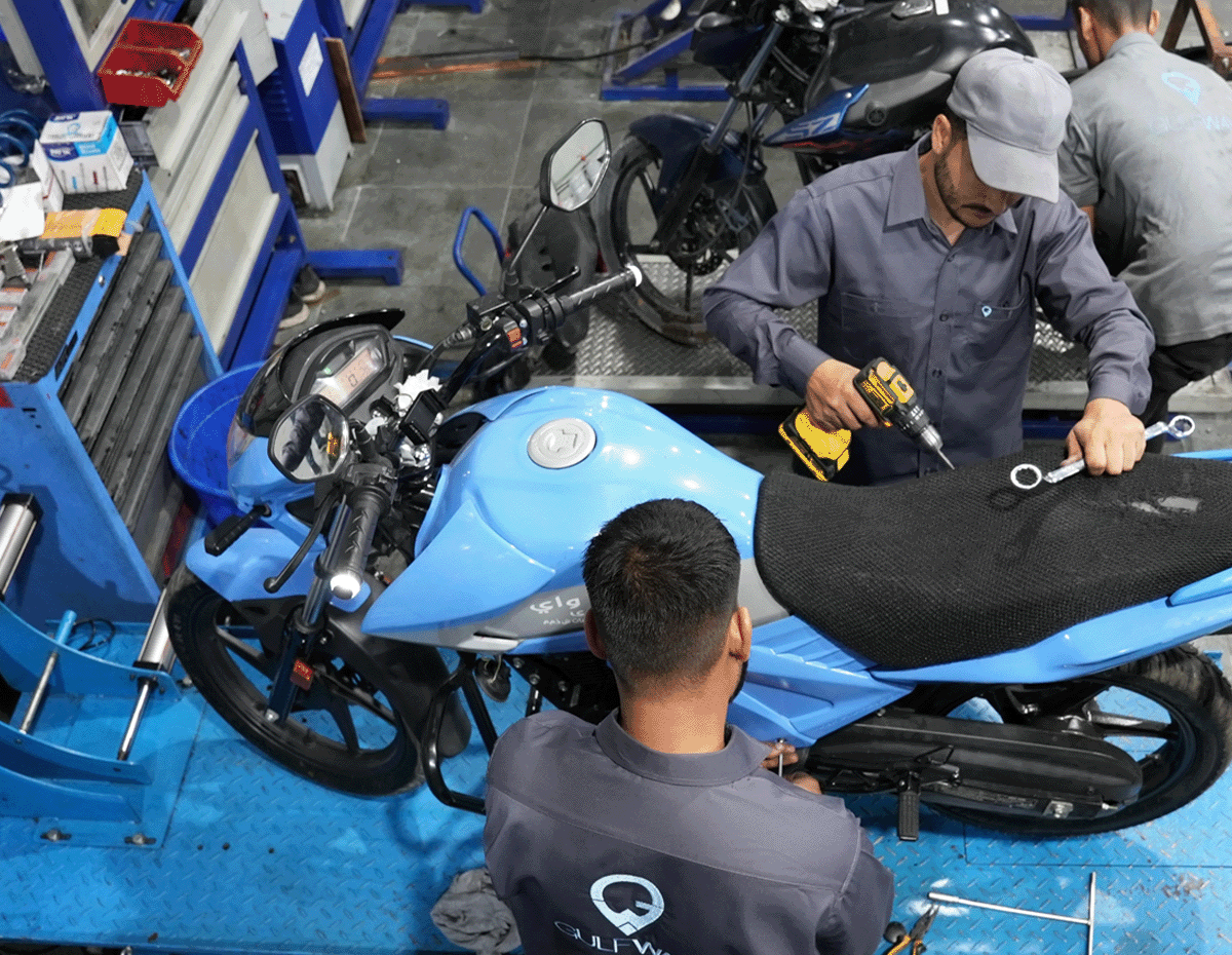 Two Gulf Way Auto mechanics repairing Gulf Way delivery motorbike with tools in hand